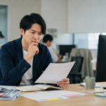 書類を見ながら、自分が仕事に向いているのか悩む会社員