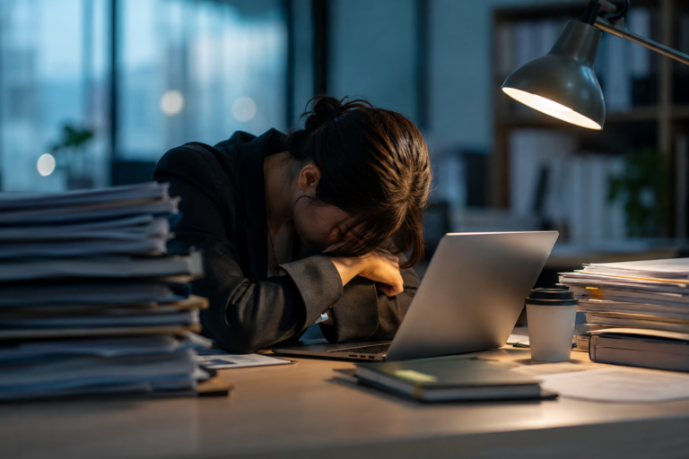 向いていない仕事を前に、書類とパソコンが並ぶデスクで疲れ切ってうつむく会社員