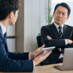 新しい仕事のやり方を提案する部下に、腕を組んで難色を示す上司