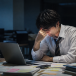仕事がキャパオーバーし、深夜のオフィスで疲れながら働き続ける会社員