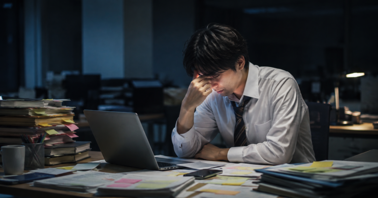 仕事がキャパオーバーし、深夜のオフィスで疲れながら働き続ける会社員