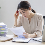 資料を何度も確認しながら仕事をする女性
