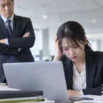 上司に厳しい表情で見られながら、仕事のミスや遅れに悩む会社員