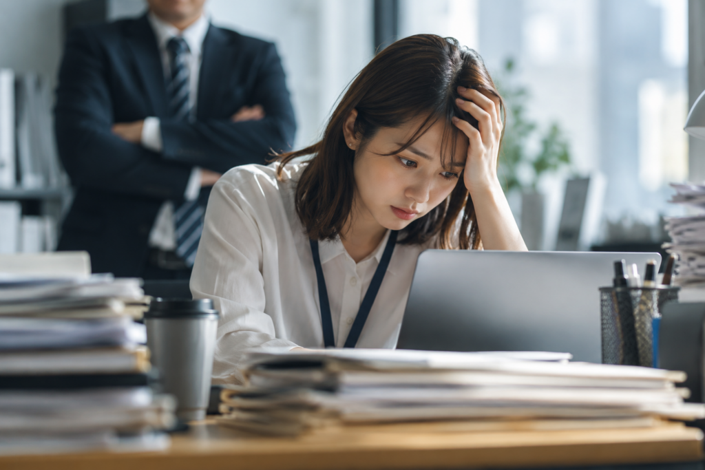仕事が遅いと言われて悩む会社員と、その様子を見る上司